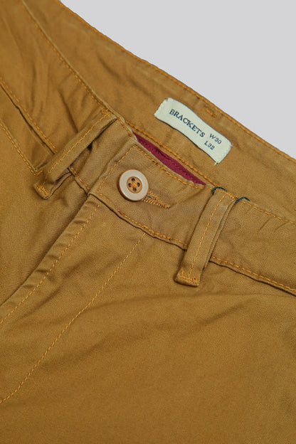 Brown pants waist detail with button closure and BRACKETS label tag.