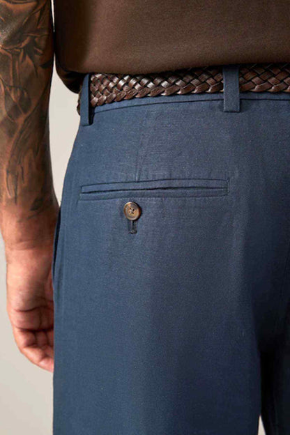 Navy jeans close-up with braided belt, button fly, and front pocket
