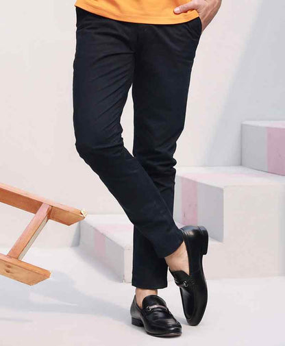 Dark fitted chinos, slim taper to ankle, belt loops; standing view