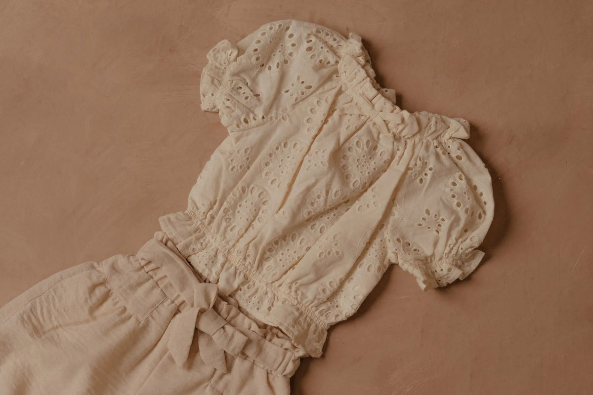 Cream eyelet puff-sleeve blouse with gathered neckline, elastic cuffs, and bow