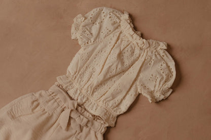 Cream eyelet puff-sleeve blouse with gathered neckline, elastic cuffs, and bow