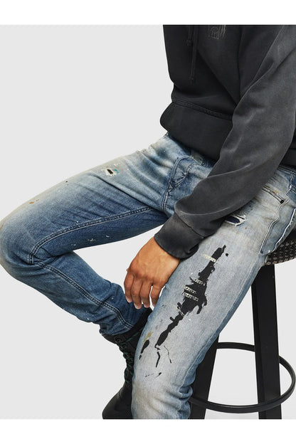 Indigo denim jeans knee with distressed paint marks and ripped patches