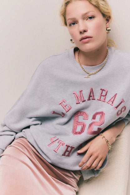 Grey sweatshirt close-up with red and blue “62” front graphic and neckline.