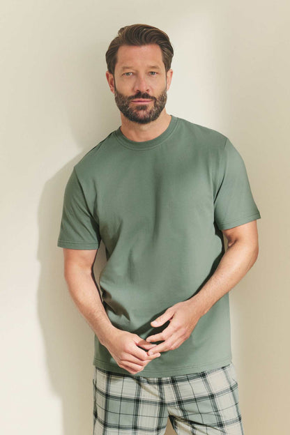 Men's green crewneck T-shirt with plaid drawstring shorts, close-up front view.
