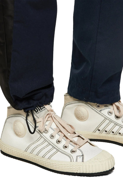 Dark blue cargo pants with ribbed cuffs and side zipper pocket, worn with sneakers