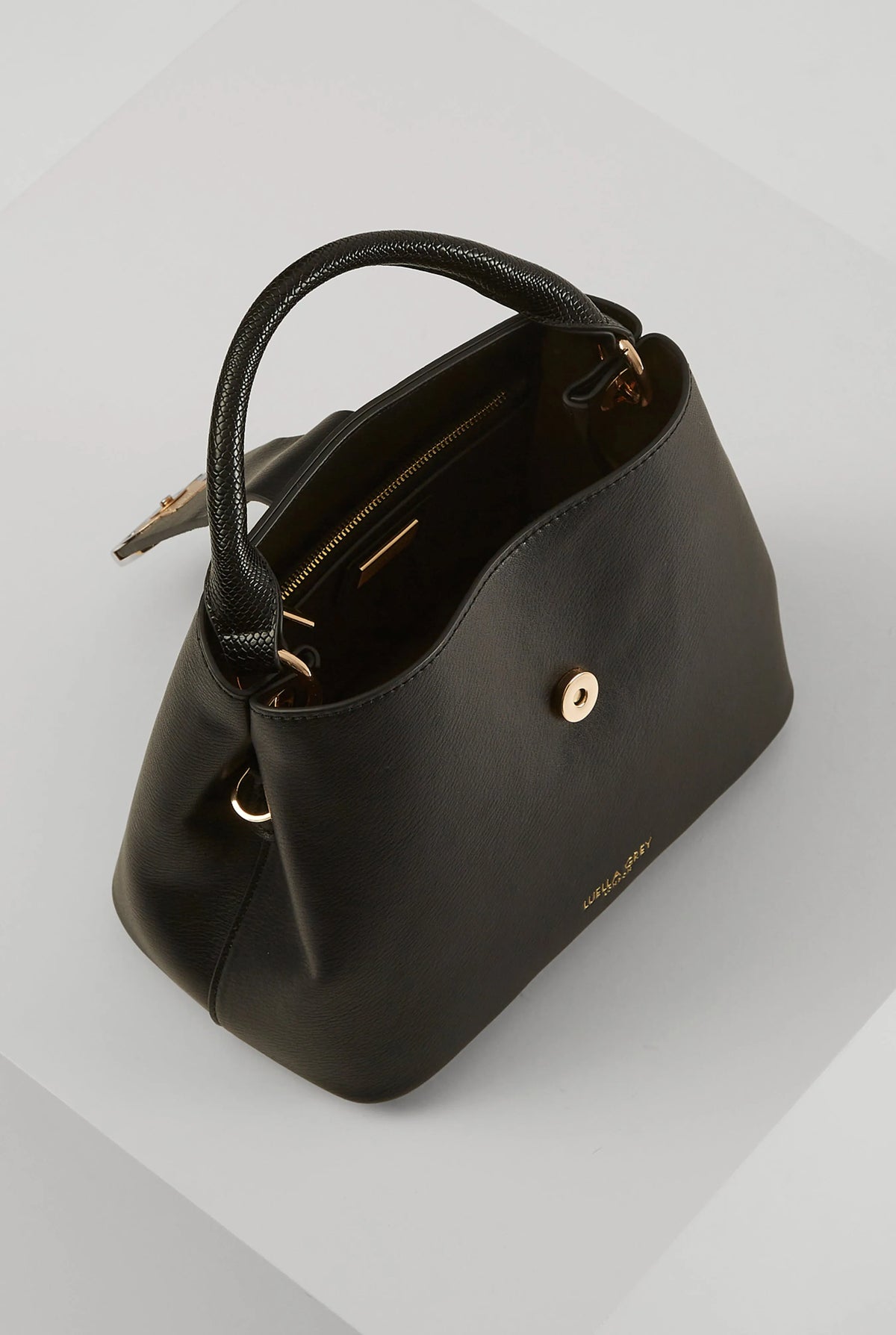 Black mini handbag with top handle, visible zipper pocket and gold-tone button