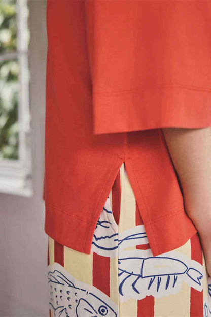 Red T-shirt hem with side slit over striped pajama pants