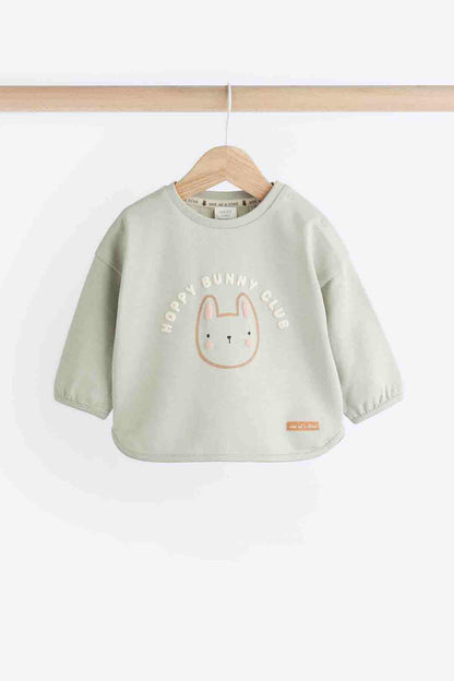 Sage green long-sleeve bunny graphic top with small logo label, front view