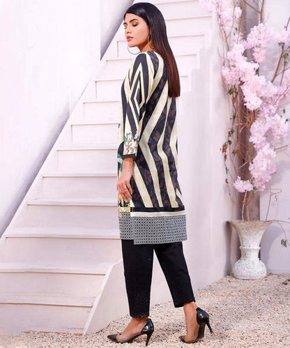 Striped long-sleeve tunic with floral hem and black pants, side profile