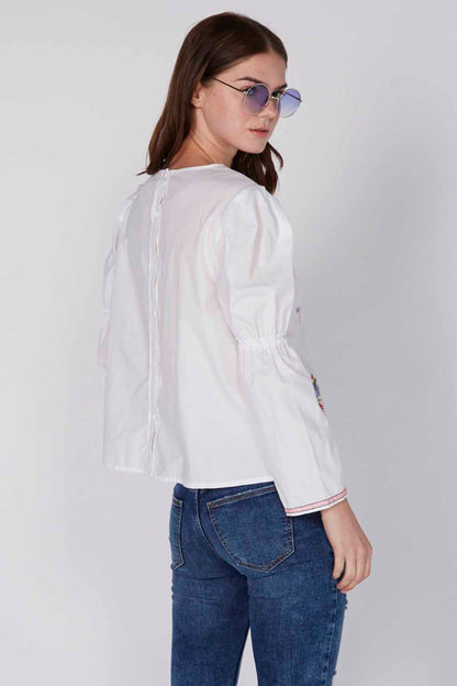 White long-sleeve blouse with gathered shoulders and embroidered trim at cuffs