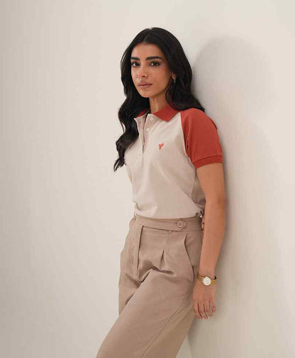 Fitted polo shirt with red collar and sleeves; khaki pleated trousers