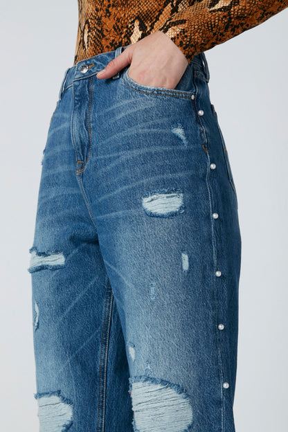 Blue distressed denim jeans with silver button detailing and ripped knee patches