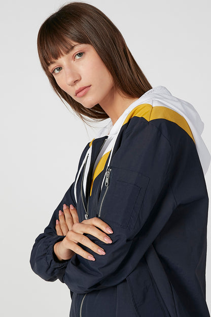 Dark navy hooded jacket detail: zip pocket and yellow/white sleeve stripe
