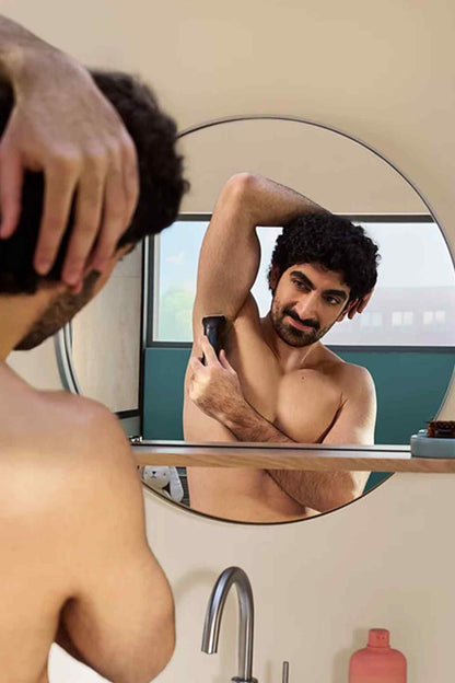 Black Philips grooming trimmer with guard close-up in bathroom mirror view