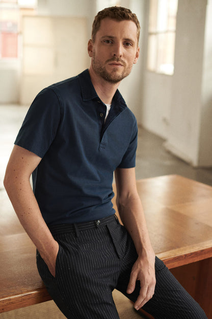 Navy pinstripe trousers with belt loops and front button closure on model