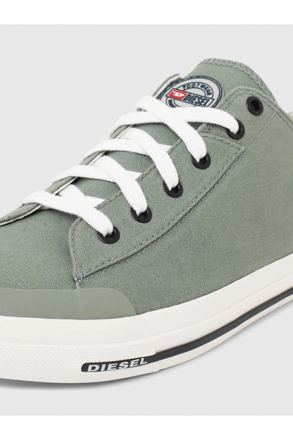 Close-up of green canvas sneaker with white laces and Diesel logo on sole