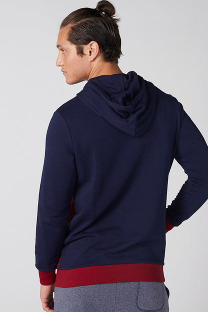 Navy hoodie with hood, red hem band, and kangaroo pocket; side view
