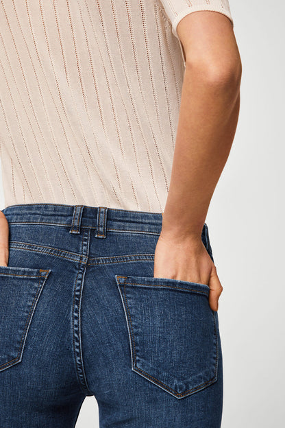 Dark blue denim jeans waist close-up with button, belt loops, and side pocket.