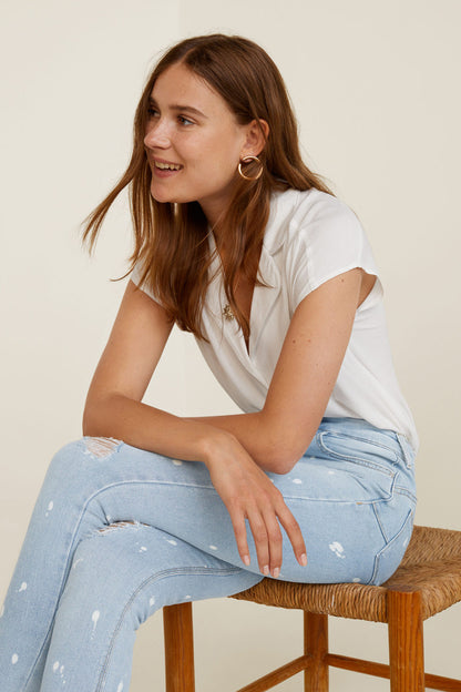 Light blue denim jeans with white speckle, ripped knees, worn while seated