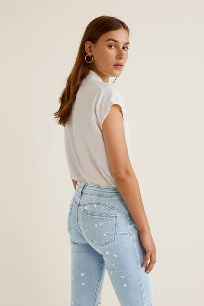 Light blue slim jeans with white speckle, ripped knees, and button fly