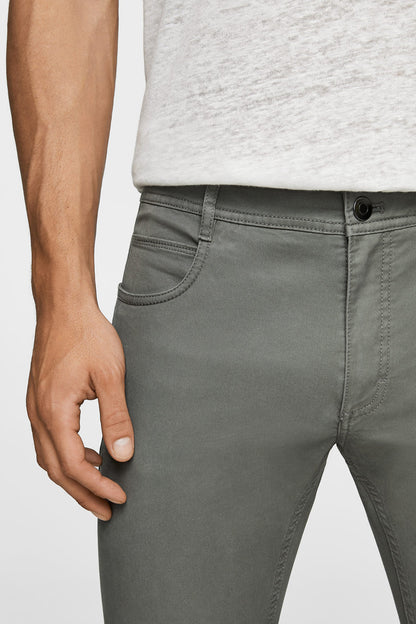 Close-up of grey slim-fit pants: front pocket and button