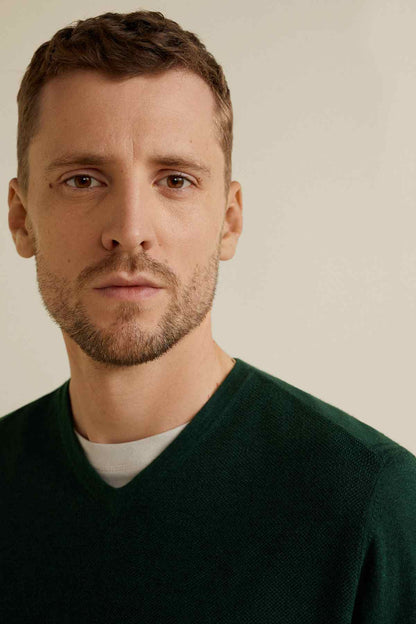 Men's dark green V-neck sweater neckline close-up, long sleeves