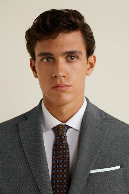 Medium grey blazer with notch lapels, patterned tie and white pocket square