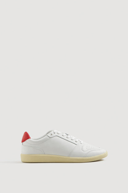 White low-top sneakers with red heel, lace-up, gum sole.