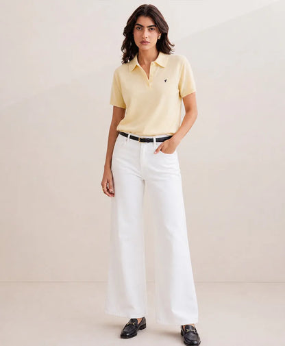 Cream polo shirt with short sleeves, collar buttons, small chest logo and white pants