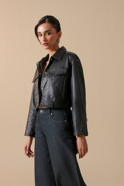 Women’s blue-black wide-leg jeans with black leather jacket, chest-up angle