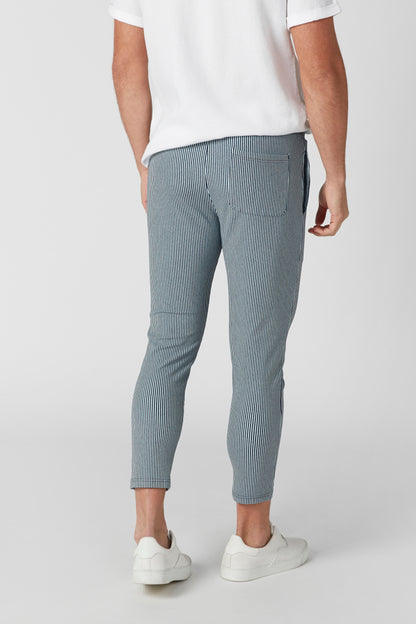 Splash cropped grey-blue pants with visible seams, paired with white sneakers