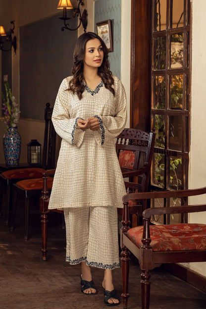 Off-white tunic set with dark trim neckline, long sleeves, and matching pants