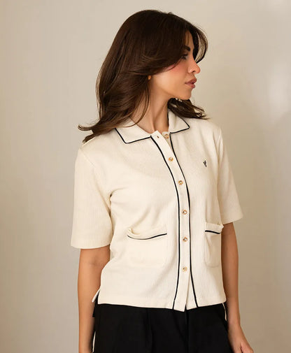 Ivory short-sleeve button-up top in side view with stand collar and contrast trim.