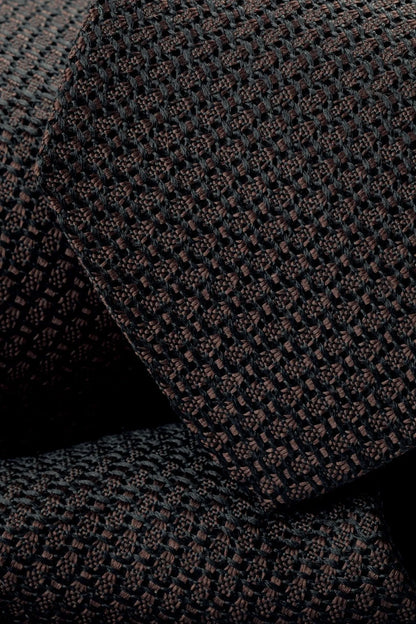 Dark brown woven tie close-up with textured geometric pattern