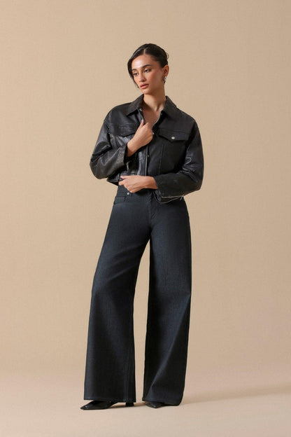 Women’s blue-black wide-leg jeans with black leather jacket, hands on collar