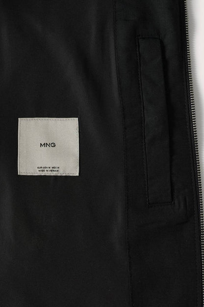 Black bomber jacket label: MNG logo on fabric tag near zipper.