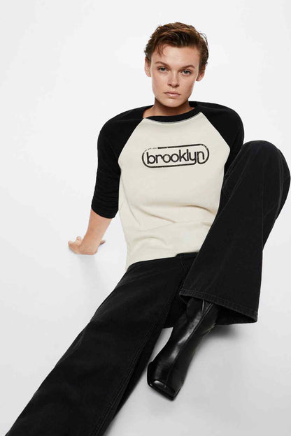 Ecru raglan baseball T-shirt with black sleeves, “brooklyn” logo, angled view