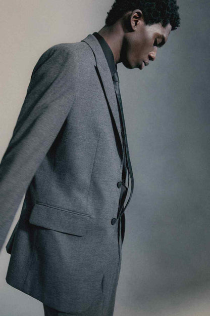 Grey suit jacket on model, single-breasted front with flap pockets