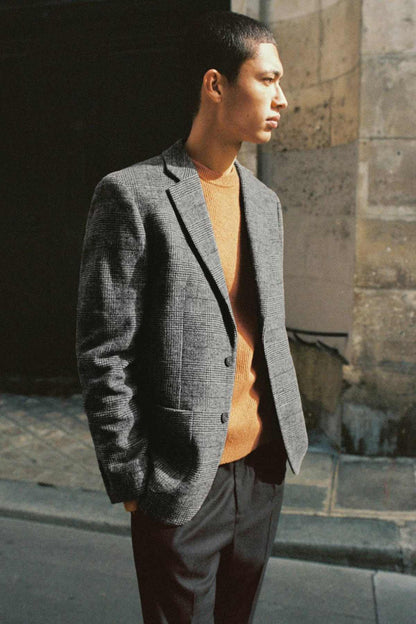 Grey textured blazer worn open over orange top, side profile