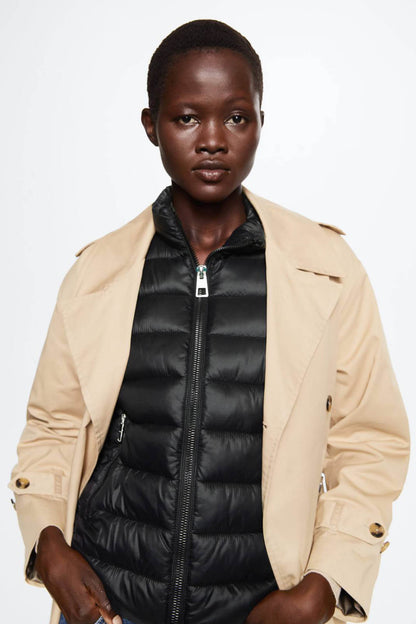 Black quilted puffer vest with front zipper, worn under a light jacket