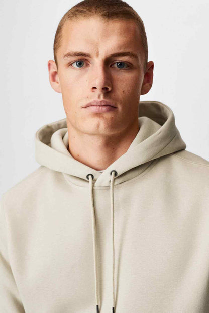 Ecru hoodie close-up with drawstring hood and ribbed cuffs
