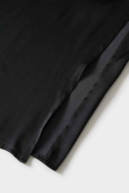 Black shirt dress fabric close-up showing hem edge and textured weave