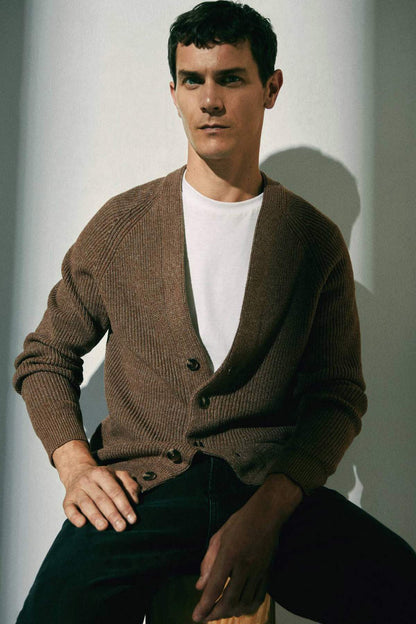 Beige knit cardigan with V-neck and button-front, model seated