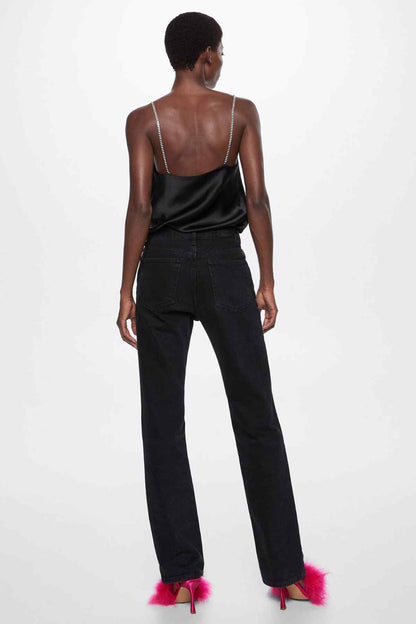Back view black satin camisole top with thin chain straps, worn with jeans