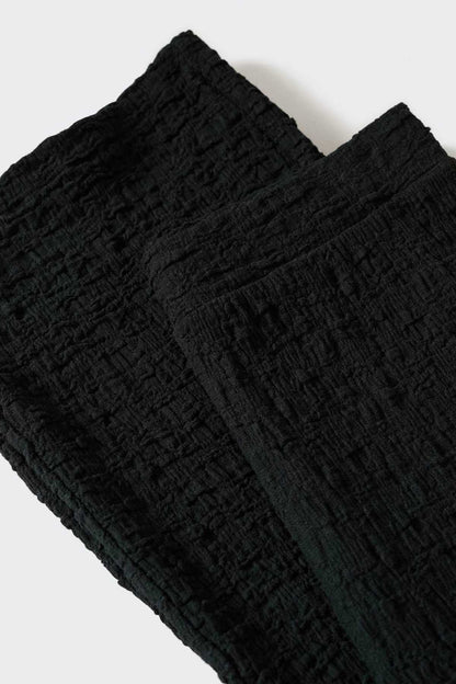 Black wide-leg trousers with textured crinkle fabric and gathered waistband