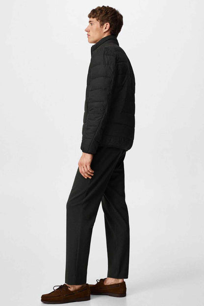 Black zip-up puffer jacket on model, side view with elastic cuffs