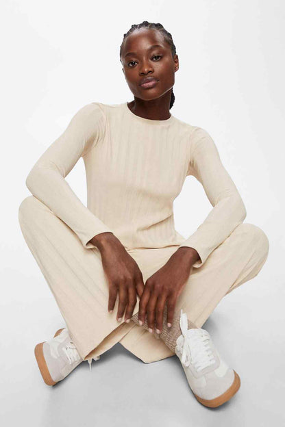 Beige long-sleeve tunic and striped wide-leg pants, seated three-quarter view