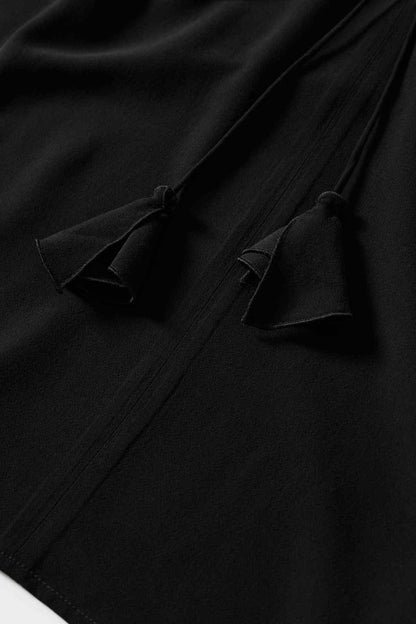Black blouse fabric detail with gathered placket and tie elements