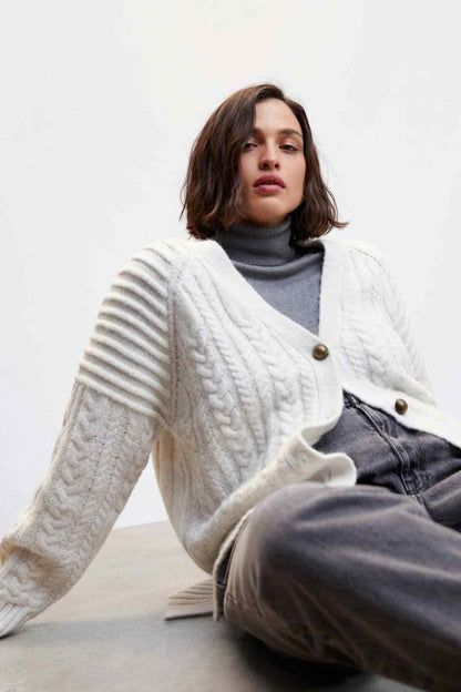 Ecru cable-knit cardigan with metal buttons and draped shawl collar