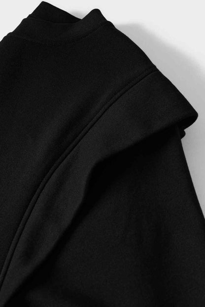 Black fabric close-up with diagonal shoulder seam and smooth knit surface